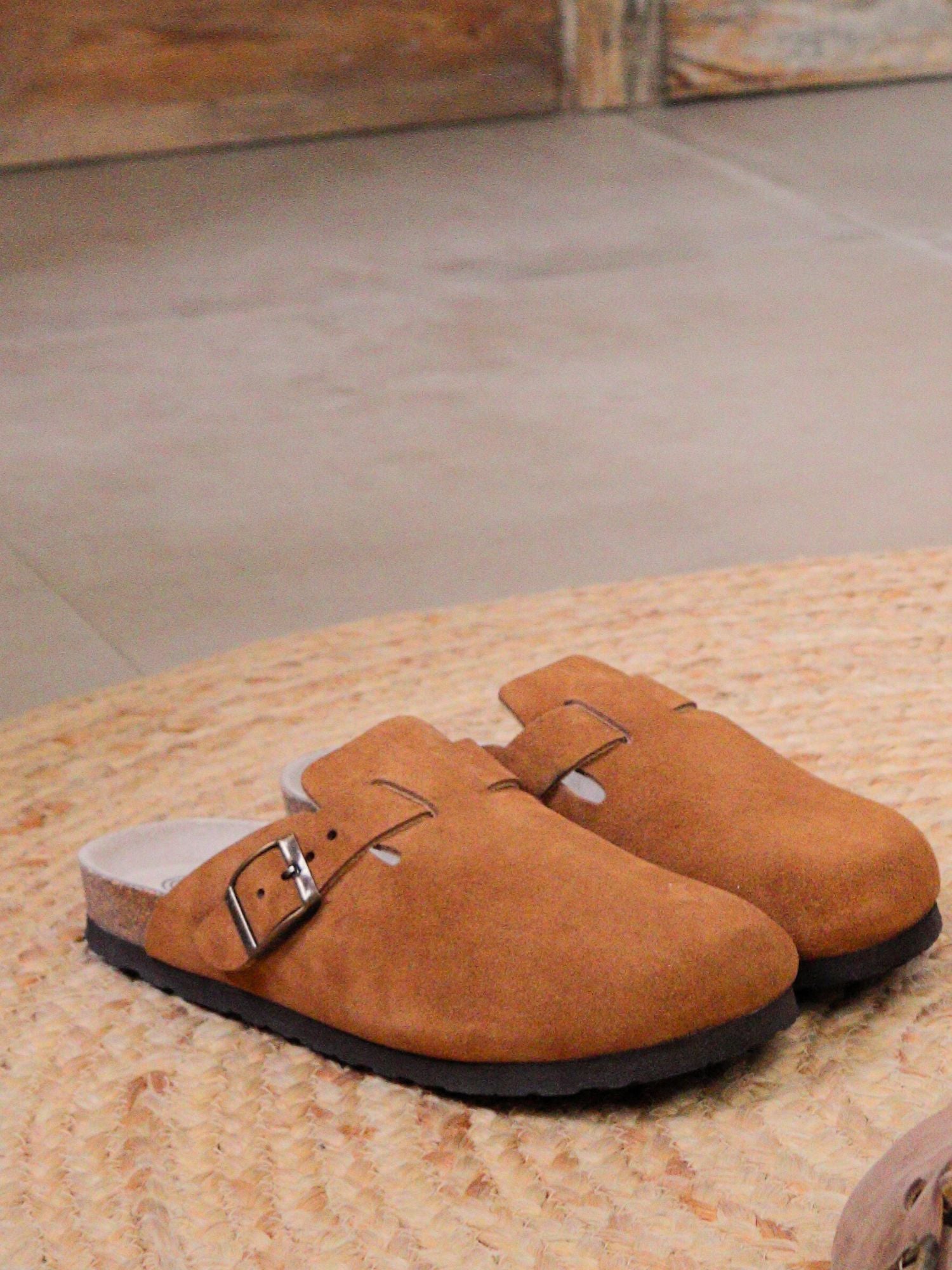 Zueco Genuins Riva  de piel serraje color marrón camel con planta anatómica de caucho corcho y hebilla ajustable metálica para hombre bodegón 